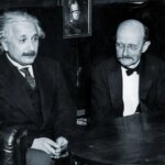 Два человека в костюмах сидят за столом, историческая черно-белая фотография.