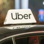 Такси Uber на ночной улице с яркой подсветкой.