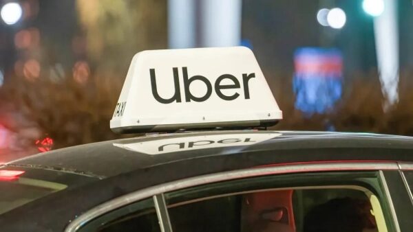 Такси Uber на ночной улице с яркой подсветкой.