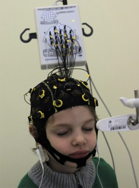 Человек с энцефалографической шапкой и проводами для мониторинга активности мозга.