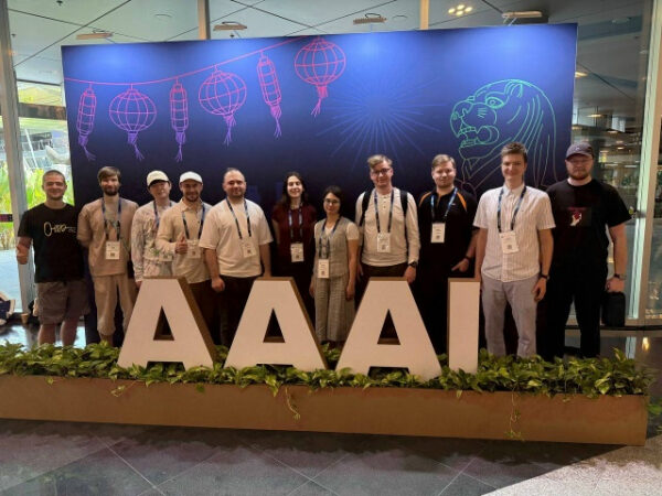 Группа людей на конференции AAAI, баннер с фонариками и львом на заднем плане.