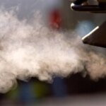 Выхлопные газы автомобиля на фоне размытых объектов, загрязнение воздуха.