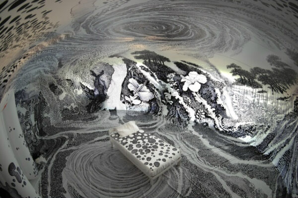 Черно-белый интерьер комнаты с абстрактными узорами и кроватью в центре.