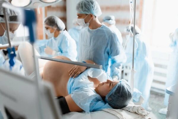 Почему роды проходят намного быстрее, если их стимулируют рано утром? 3 Роды в больнице, медперсонал в операционной одежде.