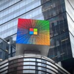 Логотип Microsoft на здании с яркой цветной подсветкой, городской пейзаж.