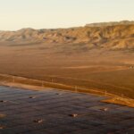 Солнечные панели в пустыне на фоне гор на закате.