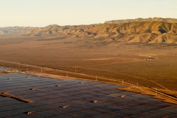 Цены на электроэнергию в этом штате резко падают по мере приближения к 100% использованию возобновляемых источников энергии. 1 Солнечные панели в пустыне на фоне гор на закате.