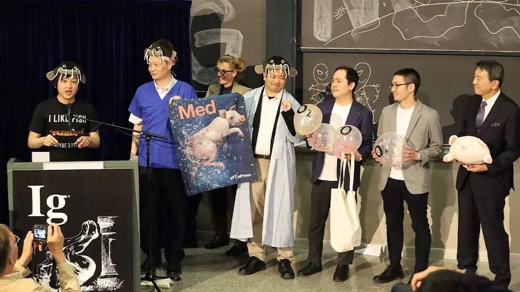 группа мужчин стоит на сцене, некоторые держат в руках воздушные шарики с надписью 