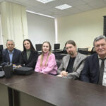 Группа людей в офисе. Компьютеры на заднем плане. Мужчины и женщины в деловой одежде.