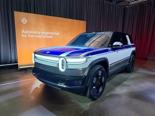 Вот как компания Rivian изменила механизм ручного открывания задней двери на модели R2. 2 Электрический внедорожник на выставке, надпись о разработке автономии для дорог впереди.
