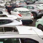 Парковка с множеством разноцветных автомобилей в плотных рядах.