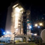 Ночной запуск ракеты на стартовой площадке, свет прожекторов, дым от двигателей.