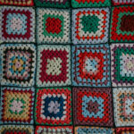 Вязаный плед из разноцветных квадратов в стиле пэчворк на фоне.