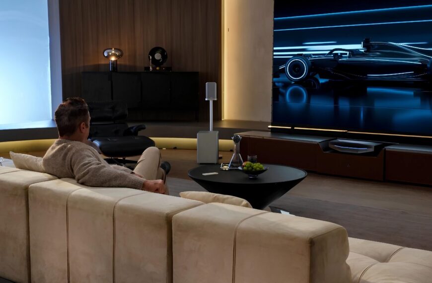 Человек смотрит гонки на большом экране в современной гостиной.