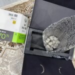 Упаковка видеокарты GeForce RTX 5070 Ti с камнями внутри на полу.