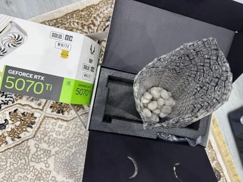 Упаковка видеокарты GeForce RTX 5070 Ti с камнями внутри на полу.