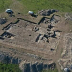 Археологические раскопки древнего сооружения с участием людей и техники.