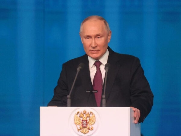 Атомные батарейки, мембраны, иммунитет: за что дали премию президента молодым ученым 3 Мужчина в костюме выступает на трибуне с гербом России, фон синие полосы.