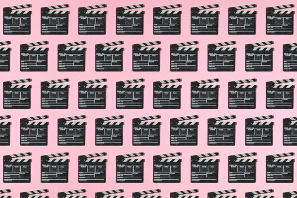 Множество кинохлопушек на розовом фоне, повторяющийся узор.