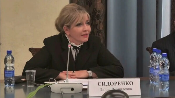 Из российских компаний через ИИ-сервисы утекло в 30 раз больше конфиденциальных данных, чем в прошлом году 4 Женщина в деловой одежде за столом на конференции, микрофон и табличка "Сидоренко".