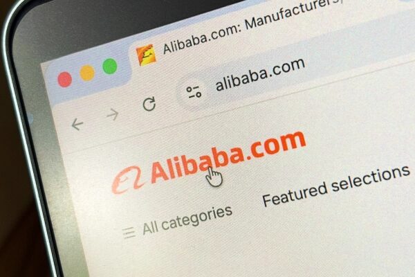 Сайт Alibaba.com на экране компьютера, крупным планом, логотип и меню навигации.