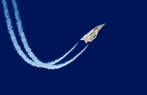 Купюра в виде самолёта летит по небу, оставляя следы.