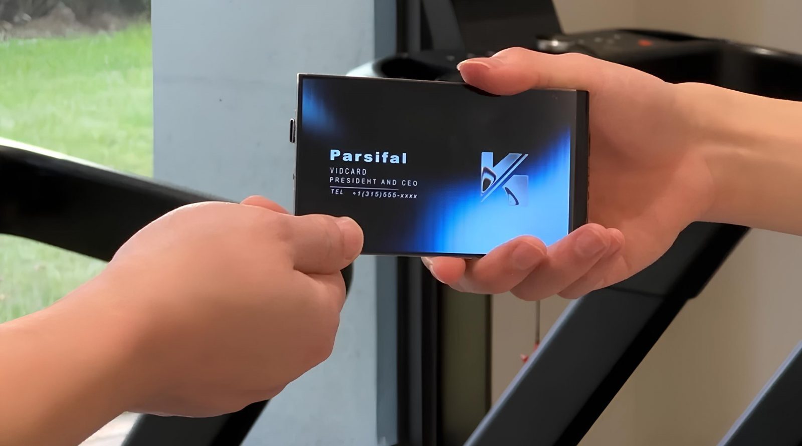 Обмен визитками: рука передаёт визитную карточку на фоне стеклянного окна.