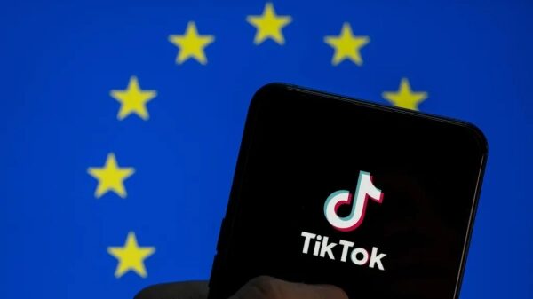 ЕС требует, чтобы TikTok отключил вызывающие привыкание функции, такие как бесконечная прокрутка, и исправил свою систему рекомендаций. 2 Телефон с логотипом TikTok на фоне флага ЕС.