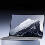 Ноутбук Lenovo с изображением горы на экране, вид сбоку, серый фон.