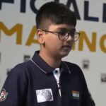 Подросток в темной футболке с индийским флагом на фоне надписи.