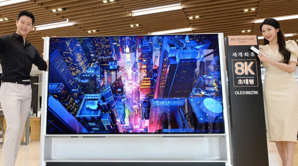 Телевизор LG OLED 8K с изображением города, представленный двумя людьми в шоуруме.