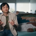 Человек объясняет рядом с медицинскими манекенами в комнате обучения.