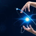 Руки вокруг светящегося атома на темном фоне. Наука и технологии.