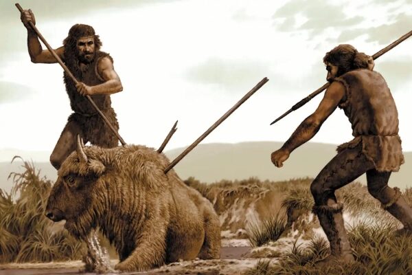 Пещерные люди охотятся на бизона с копьями, доисторическая сцена охоты на фоне природы.