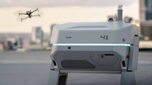 Станция зарядки дрона Skydio и летающий дрон на фоне городской панорамы.
