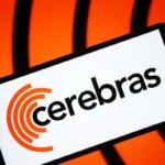 Cerebras логотип на экране устройства, оранжевый фон, технология, брендирование.