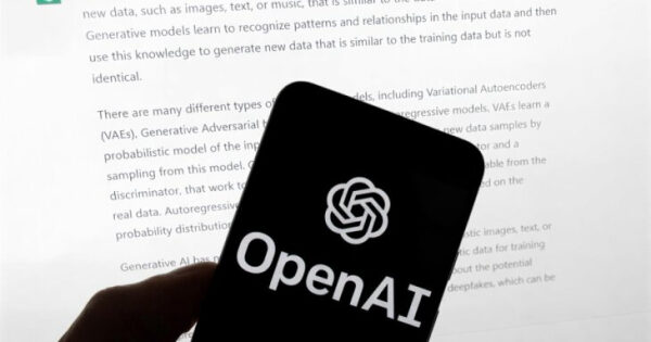 Смартфон с логотипом OpenAI на фоне текста на экране компьютера.