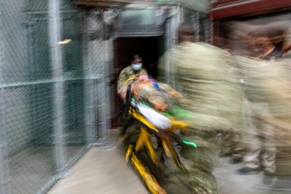 Военные несут раненого на носилках, медицинская эвакуация в движении.