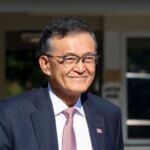 Мужчина в костюме и галстуке на улице в деловой обстановке.