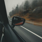 Вид из окна автомобиля на дорогу в туманном лесу осенью.