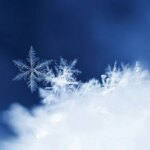 Макросъемка снежинки на фоне синего неба.