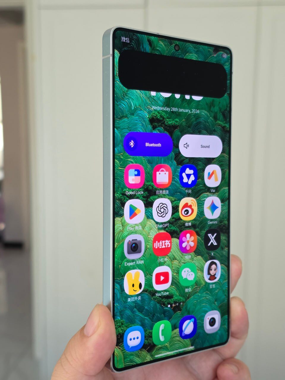 Современный смартфон с зелеными обоями и яркими иконками приложений на экране.