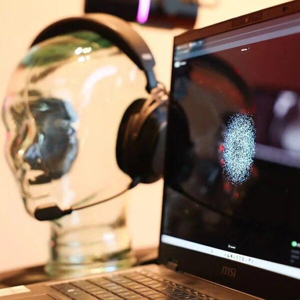 Наушники на стеклянной голове рядом с ноутбуком MSI на рабочем столе.