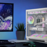 Белый игровой ПК с подсветкой рядом с монитором и клавиатурой на рабочем столе.