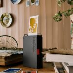 Принтер Instax печатает фото в уютной комнате, декорированной картинами и цветами.