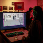 Девушка в наушниках играет в ретро-игру на выставке видеоигр, вечерняя атмосфера.