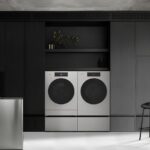 Современная кухня с черными шкафами, стирочной техникой и металлическим островом.