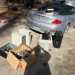 Серый кабриолет, коробки с компьютерными комплектующими на улице.