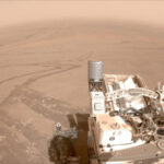 Марсоход на поверхности Марса с видимыми следами на песчаном ландшафте.