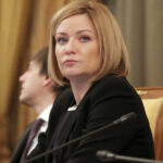 Женщина на деловой встрече, смотрит в сторону, формальная обстановка, микрофоны.